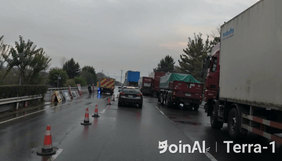 JoinAI Terra generated video frame showing a daytime road scene 7 with multiple vehicles and traffic cones on a rainy day.