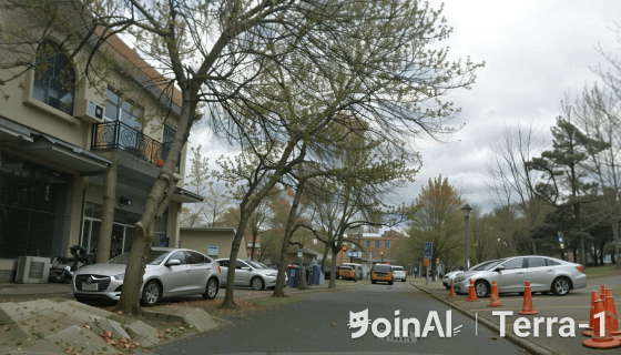 JoinAI Terra generated video frame showing a daytime road scene 9 with multiple vehicles and traffic cones on a cloudy day.